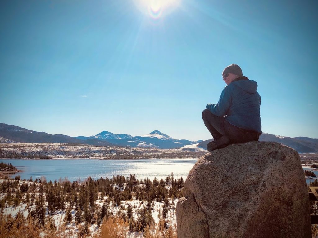 Joshua Saxton of Centered sitting on a rock looking over a snowy landscape.