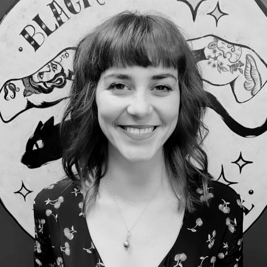 black and white photo of Jennifer Little smiling in a black, cherry-patterned dress