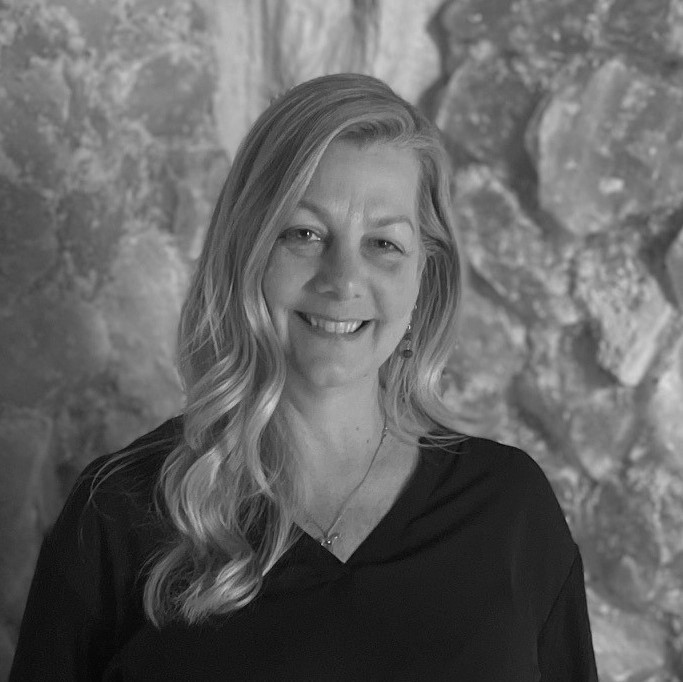 black and white photo of Jennifer Little smiling in a black, cherry-patterned dress